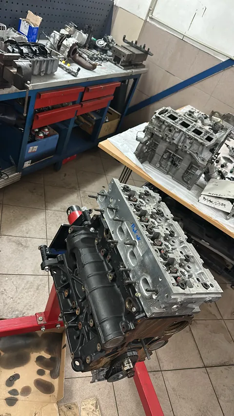 Rozebraný motor a hlavy válců na pracovním stole.