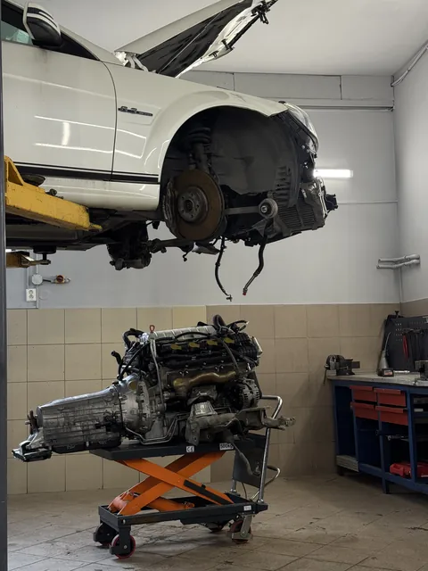 Vozidlo na zvedáku a demontovaný motor pod ním.