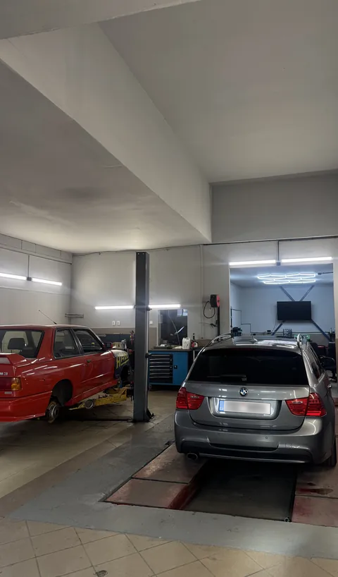 Pracovní prostor dílny s vozidly na servisních plošinách.