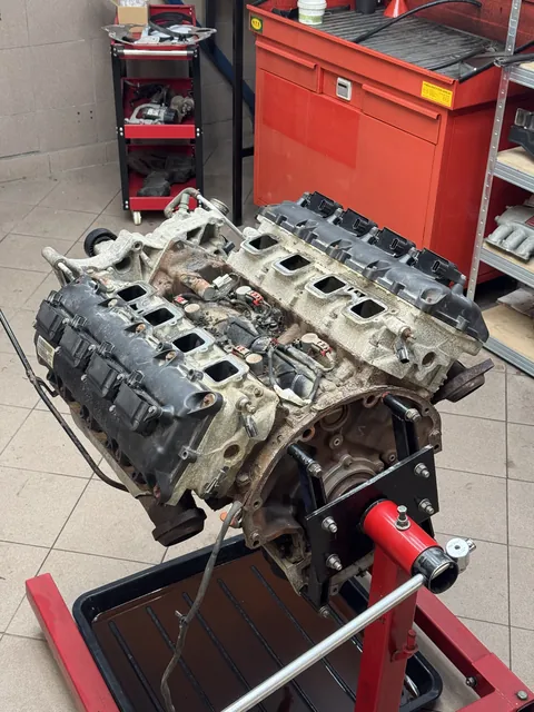 Rozebraný motor s odkrytými válci na stojanu.