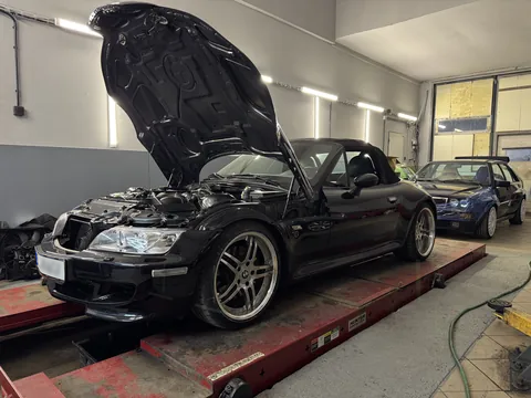 Černé BMW roadster během opravy v dílně.